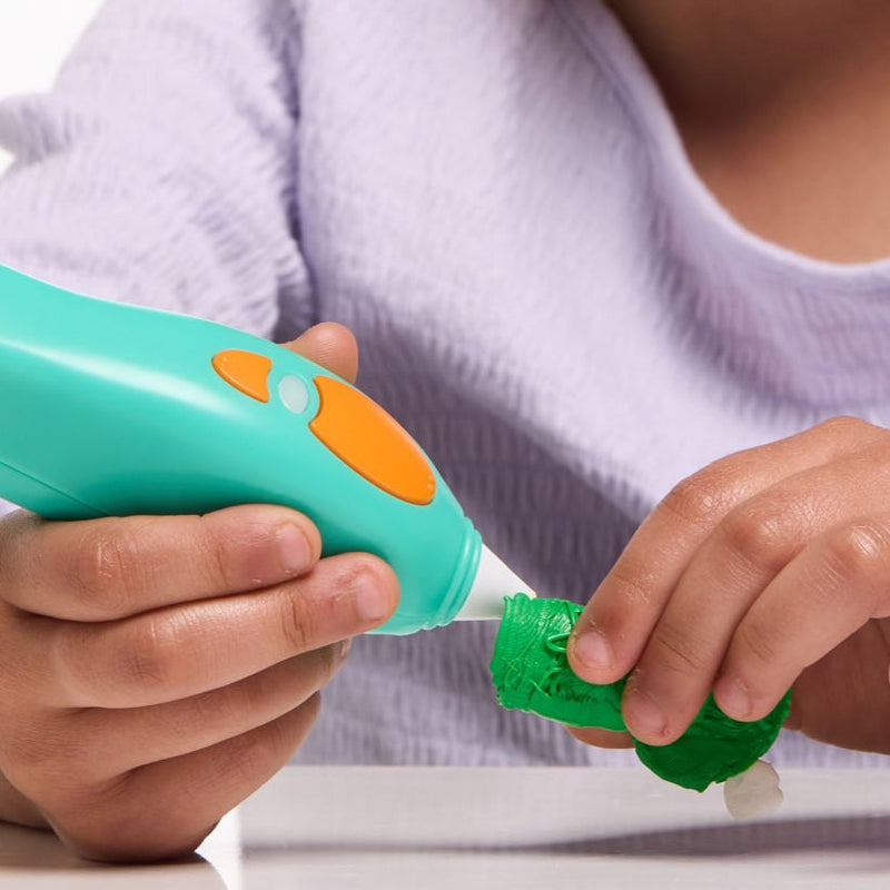 Child using a Start+ pen to add finishing touches to a green frog finger puppet.