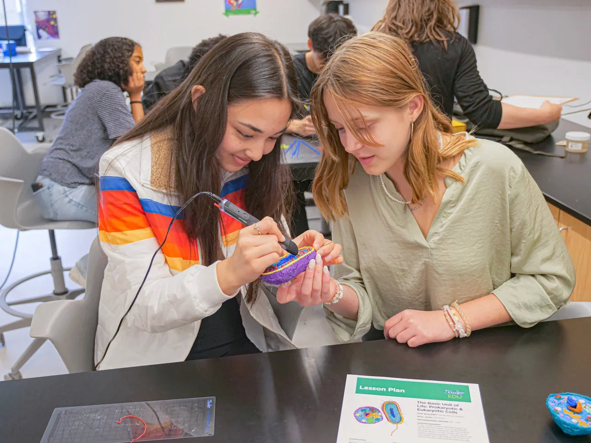 Two young women working on a project at a table with a 3Doodler Pen.